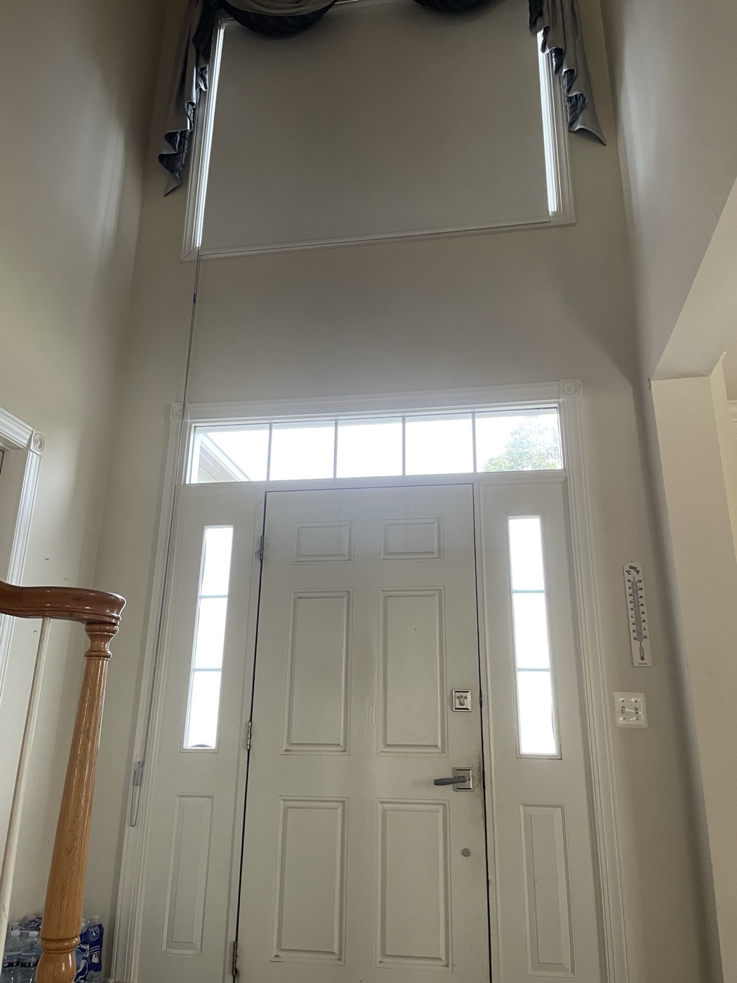 Roller shade installed beneath the swag valance in the two-story entryway, after