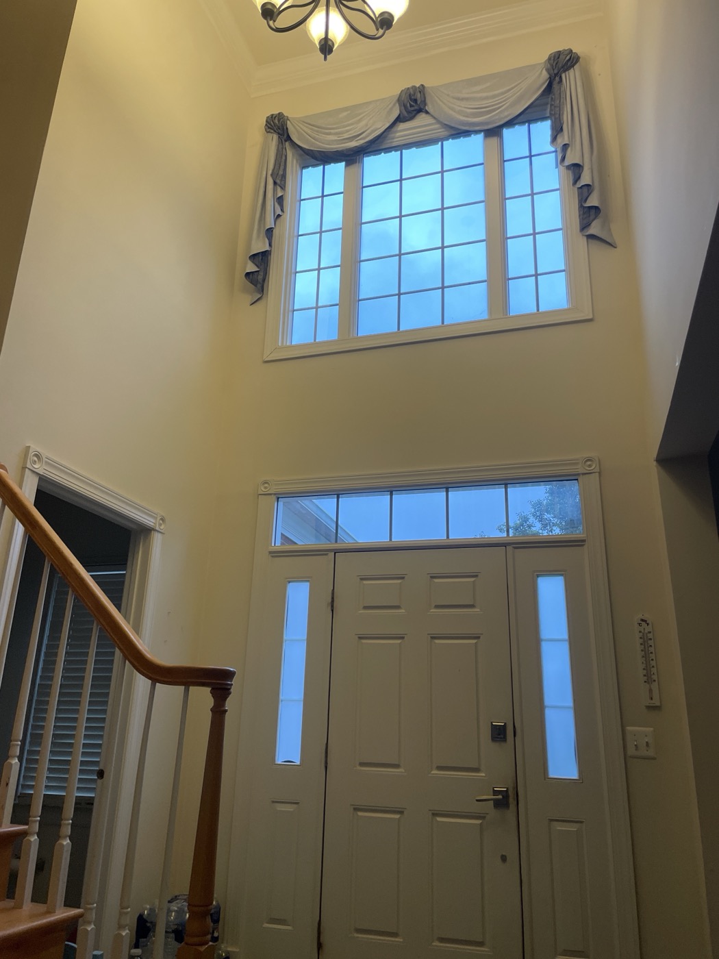 Two-story entryway window with a decorative swag valance, before the roller shade