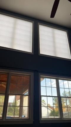 Cellular shades on the two top windows of a two-story wall