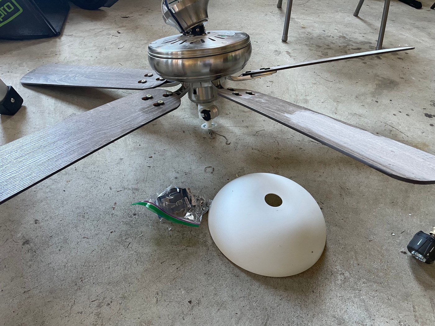 Old ceiling fan with a pull chain, taken down and laid on the floor, before the replacement