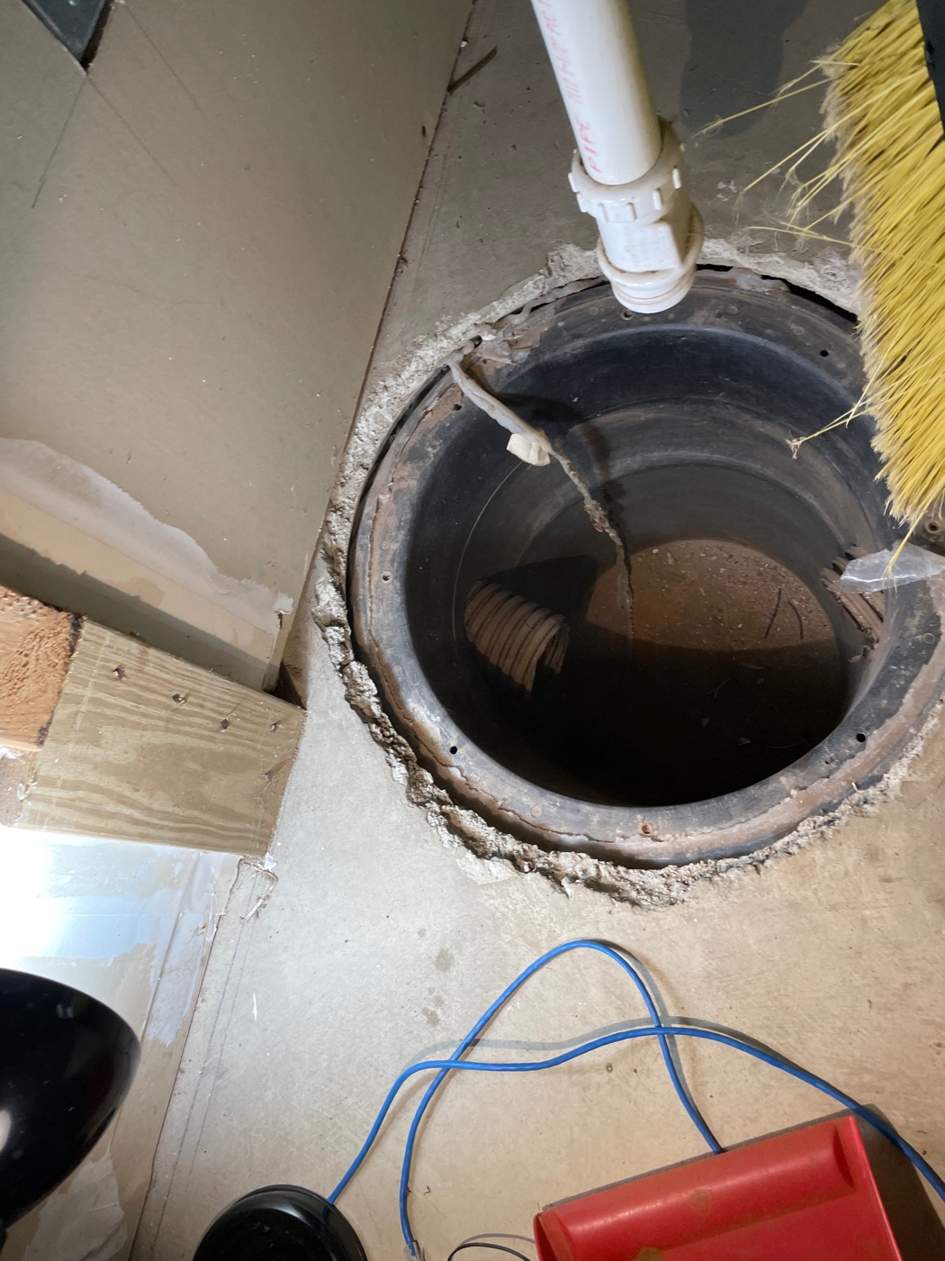 Basement sump pit with a discharge pipe above it, before